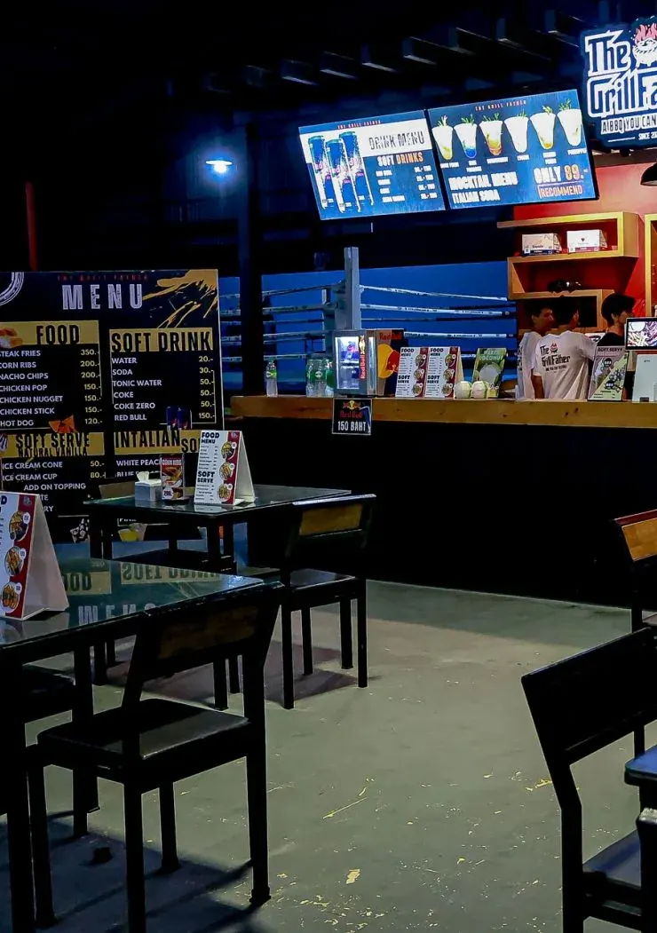 Food and soft-drink menu board beside the tables, with the ring ropes and the drinks counter behind